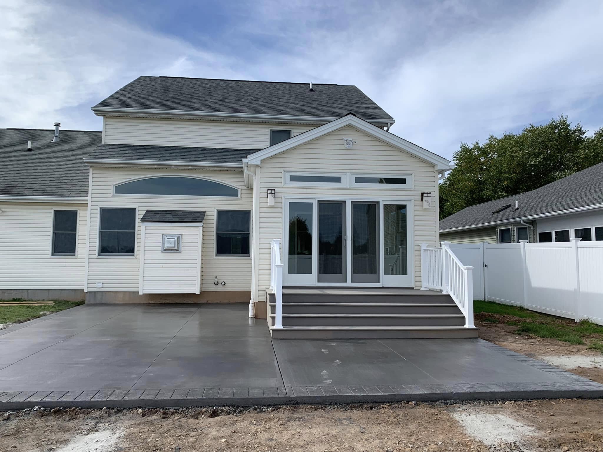 New addition exterior with stamped concrete patio, sunroom entrance, and finished siding by Fournier Construction &amp; Excavation.