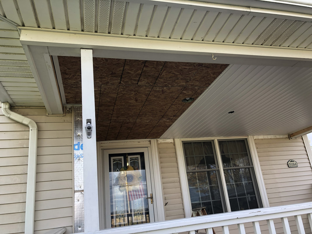 Porch ceiling renovation showing mix of OSB sheathing and installed white vinyl soffit panels.