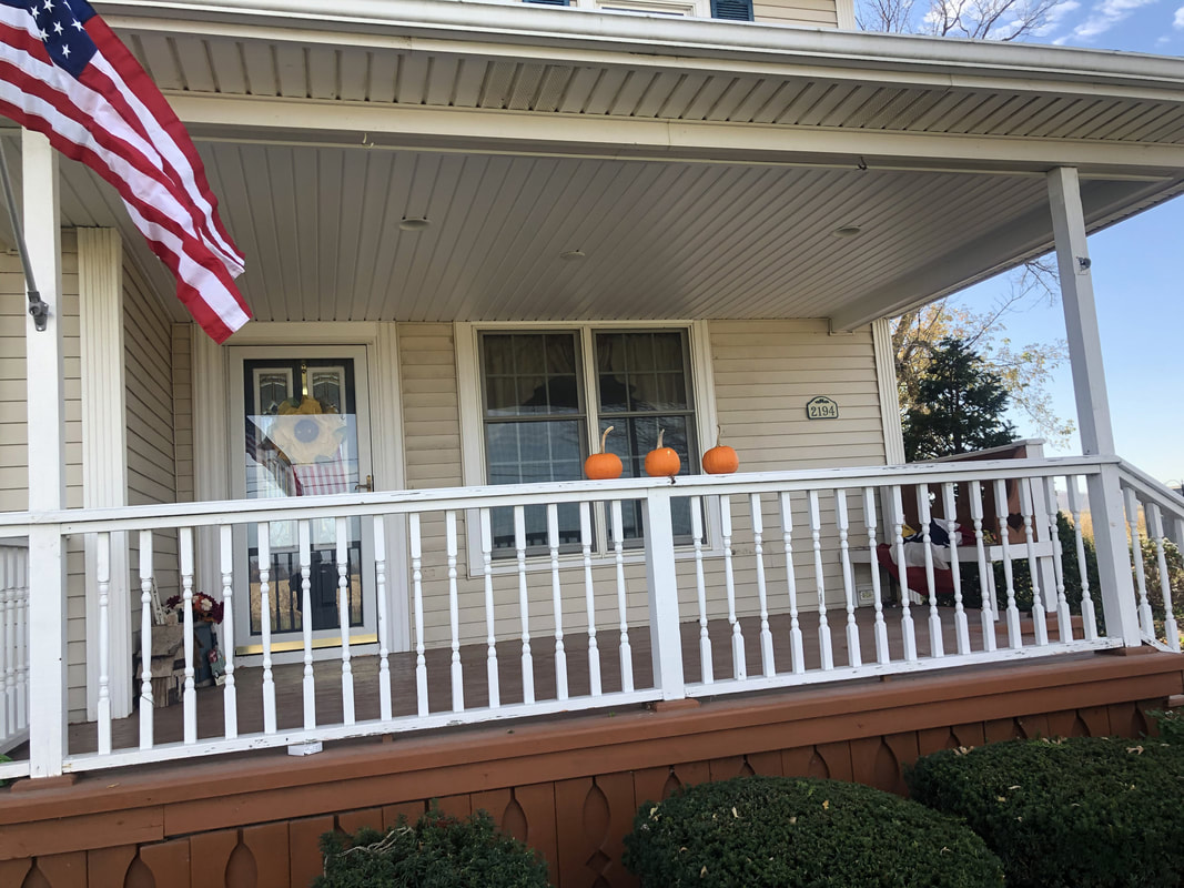Front porch with American flag and pumpkins, featuring newly installed white vinyl ceiling panels